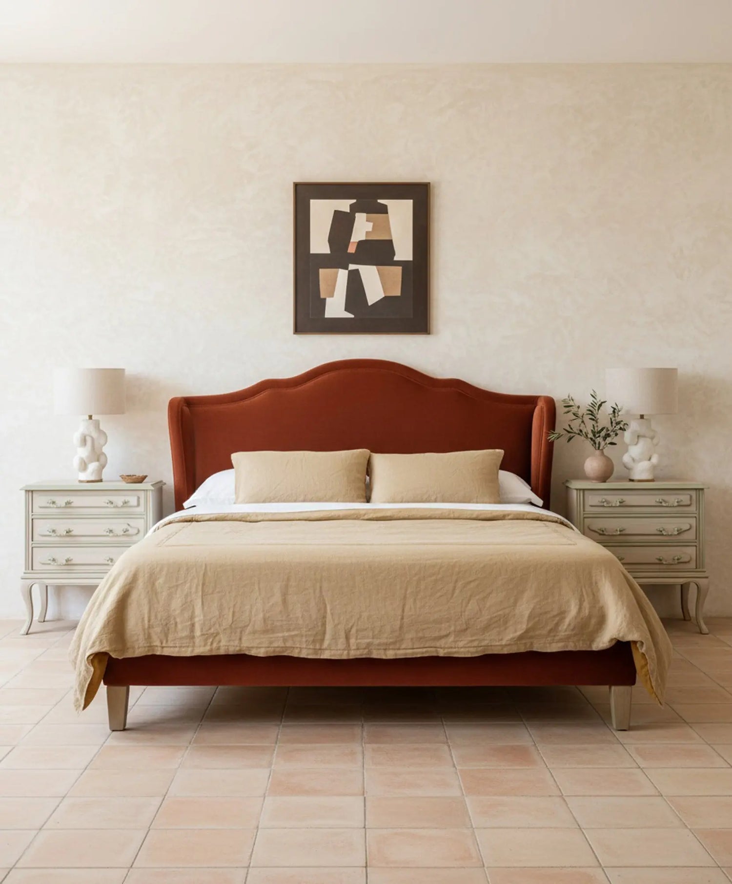 Dormitorio decorado con cama de cabecero terracota y dos mesillas de noche clásicas restauradas.