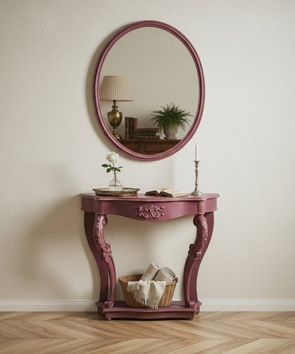 Consola rosa decorada en ambiente de salón clásico con espejo redondo y lámpara de mesa