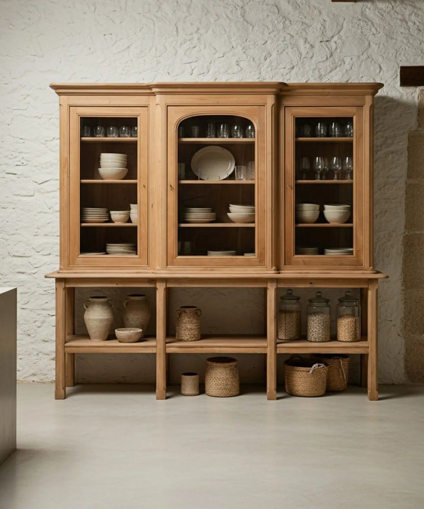 Alacena Lumière decorada con vajilla blanca, jarrones de cerámica y libros antiguos en un salón luminoso de estilo europeo.