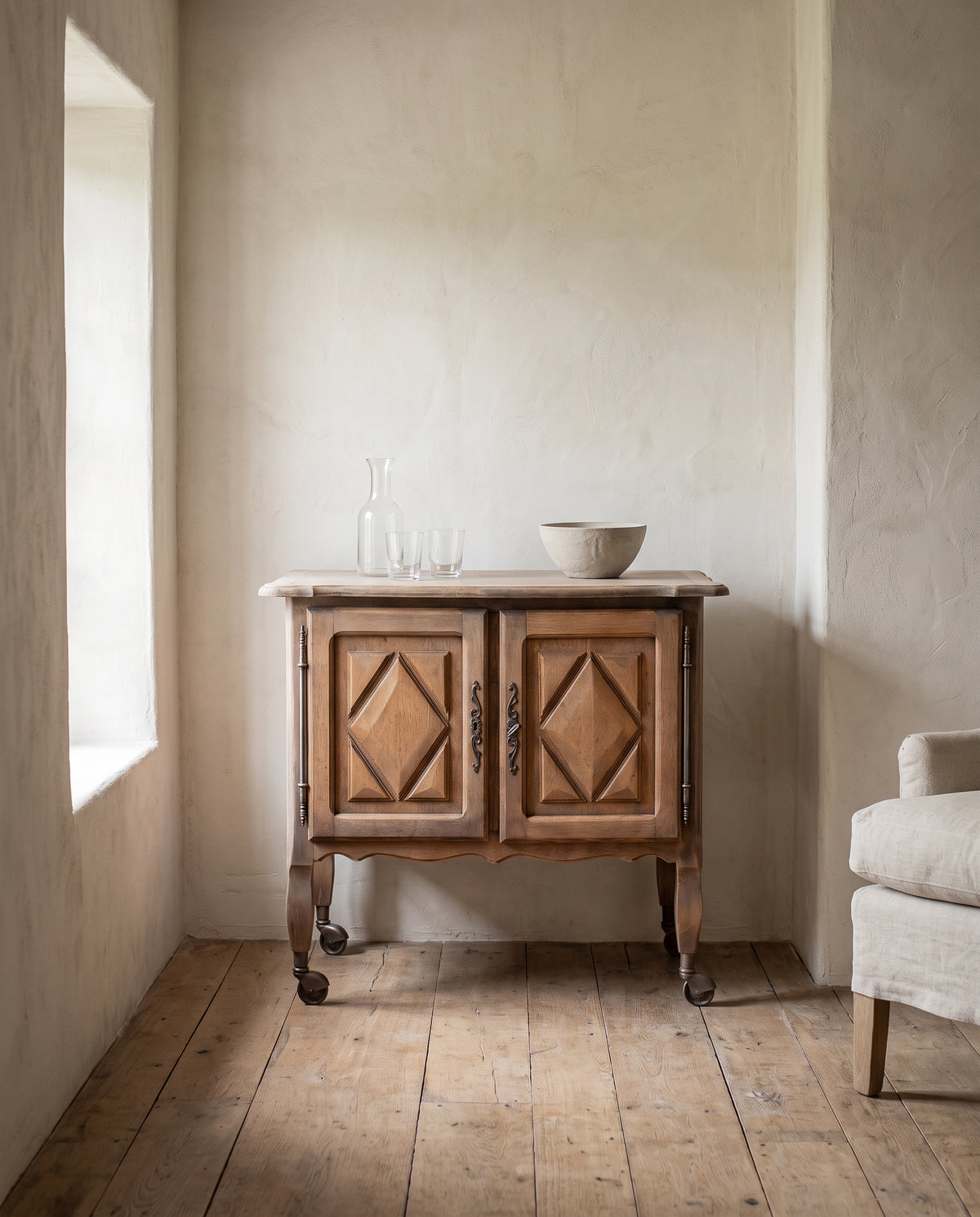 Mueble auxiliar vintage de roble con ruedas en salón con ventana y butaca de lino — Antique Arte y Decoración
