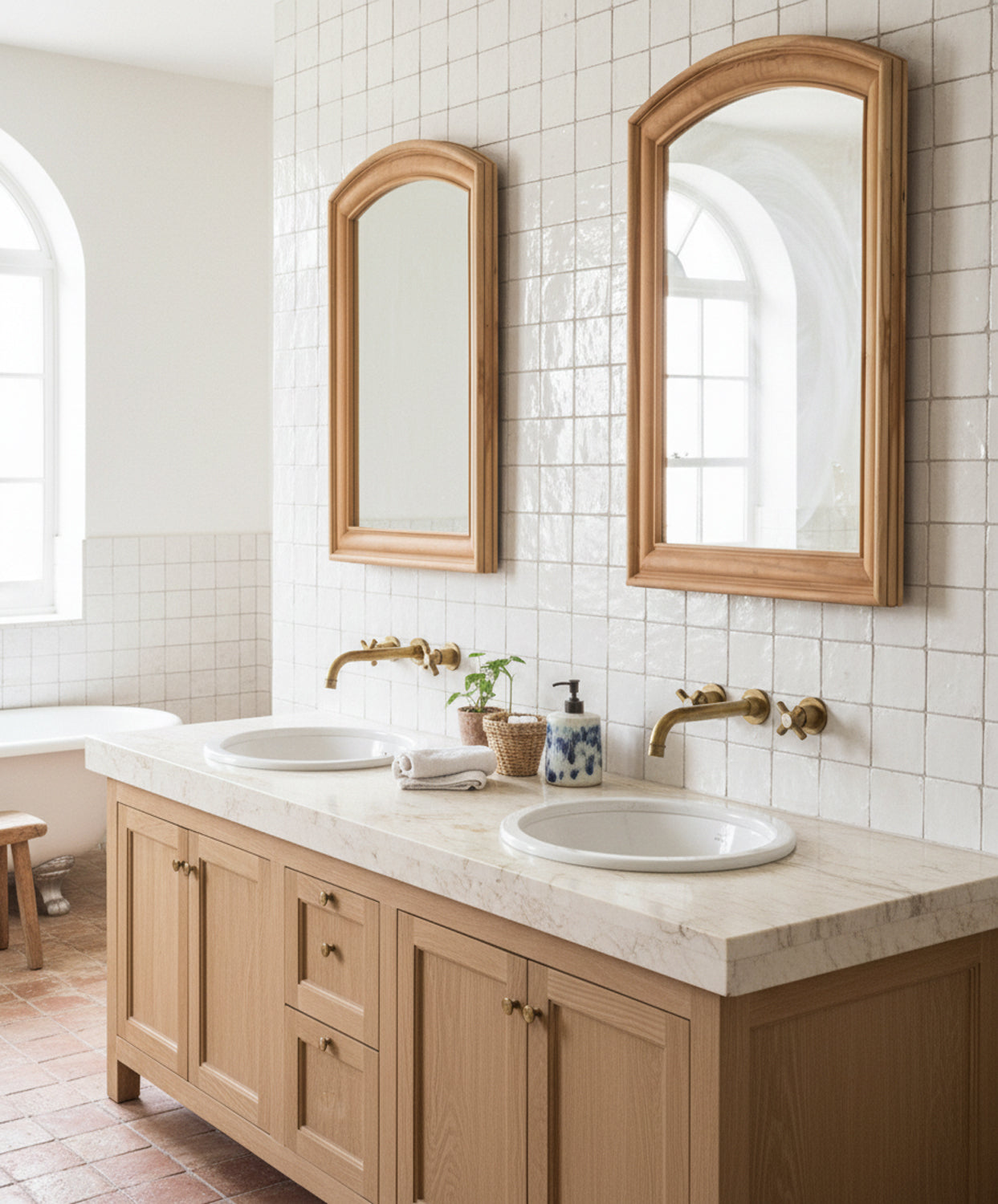 Dos espejos de madera arqueados colocados sobre lavabo doble en baño de estilo mediterráneo