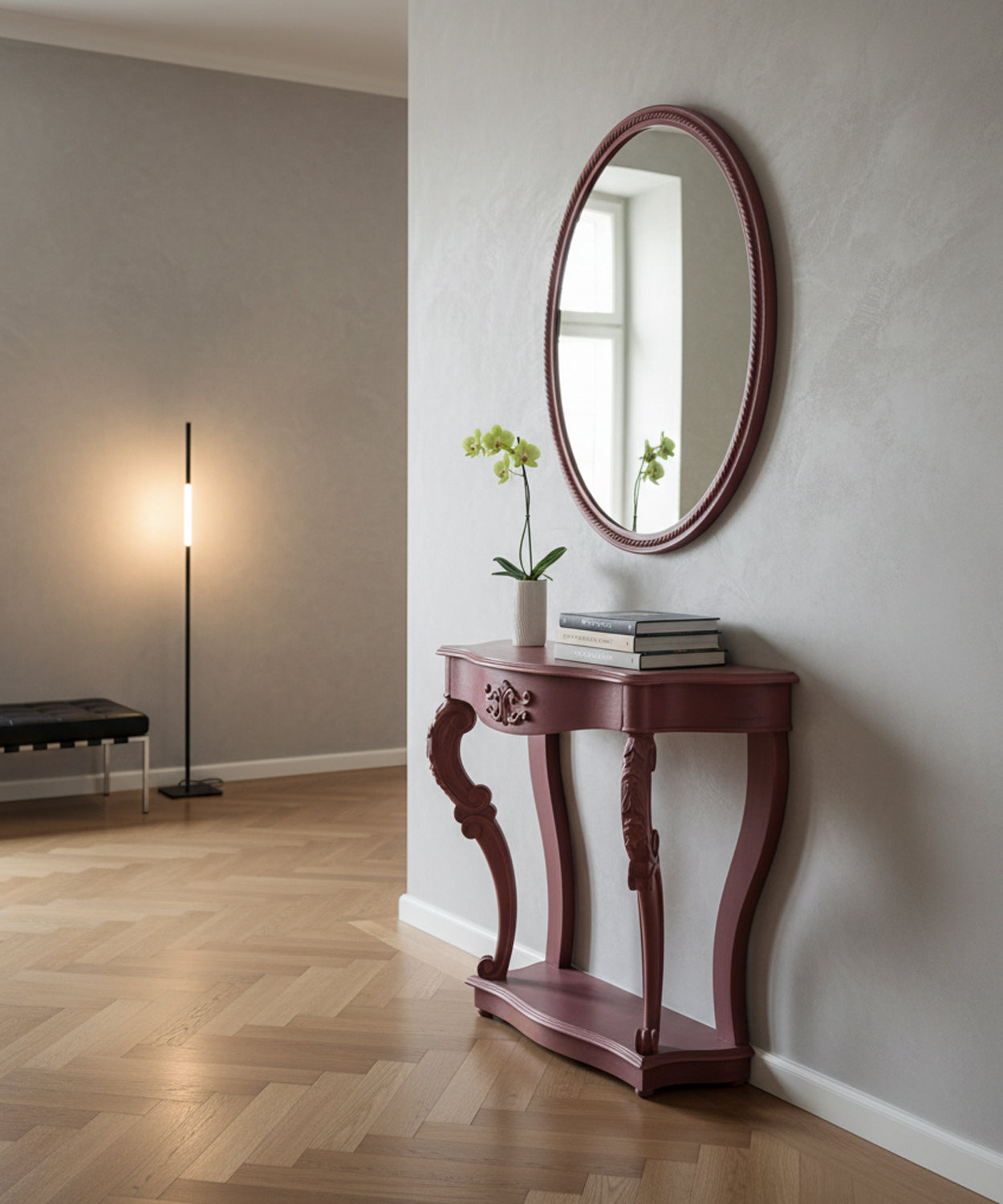 Consola estilo francés en un pasillo moderno con paredes grises, espejo ovalado y decoración floral minimalista