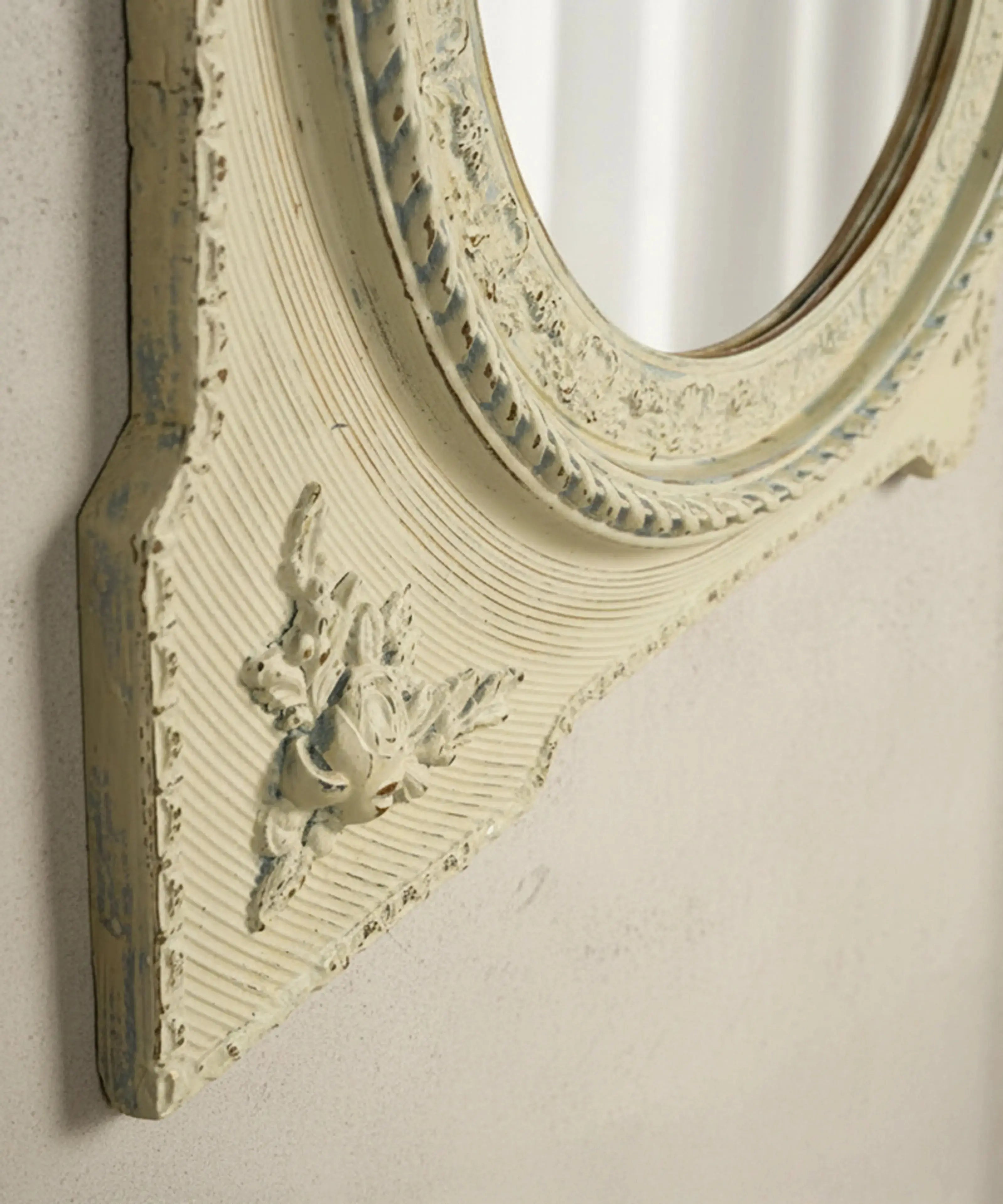 Detalle de aplique de rosas en relieve y pintura decapada en marco de espejo vintage.