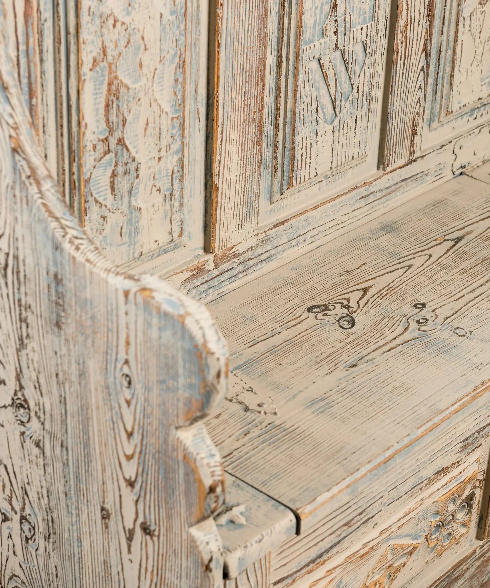 Primer plano de la veta de madera de pino maciza con pintura envejecida en tonos blanco y azul claro.