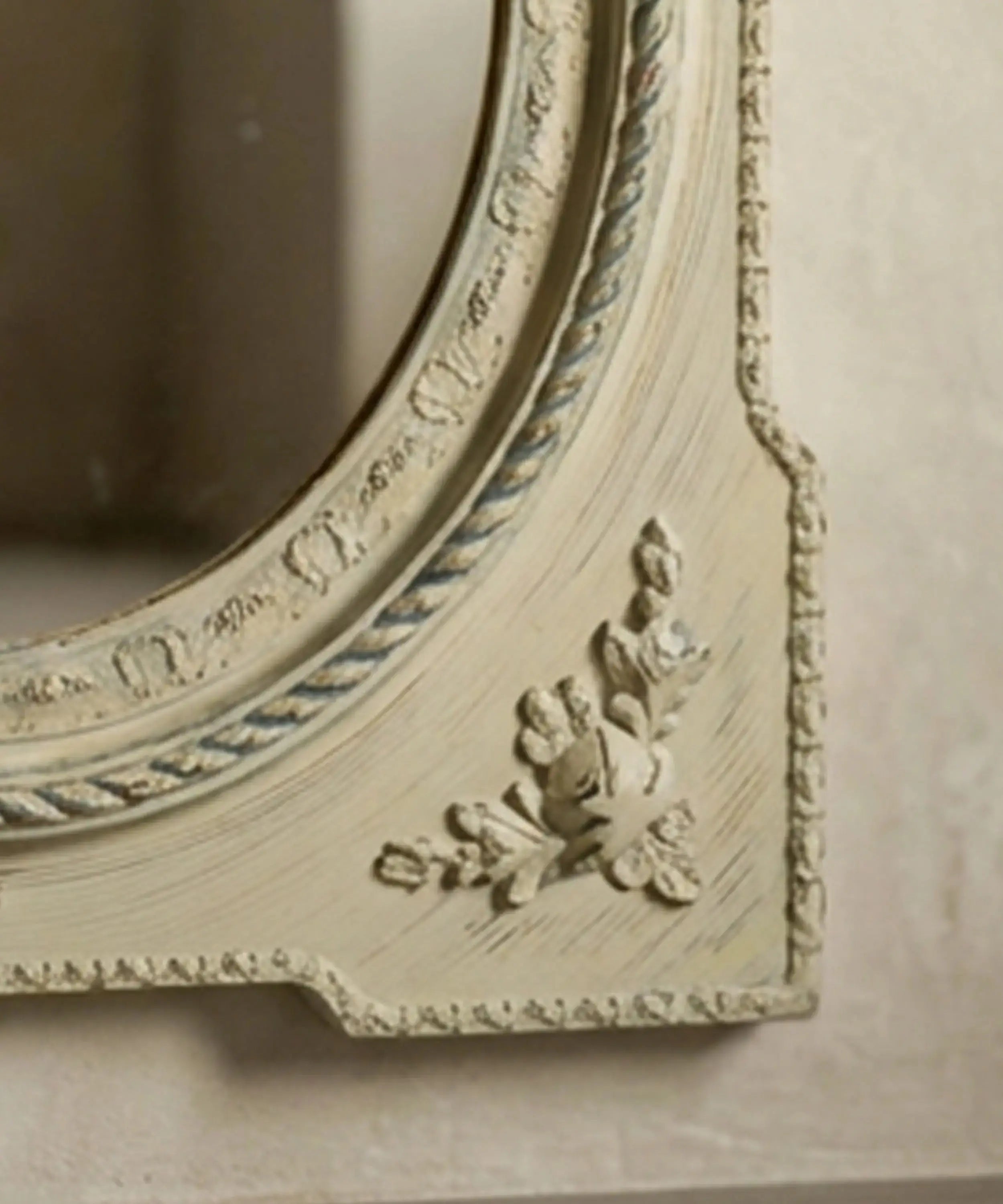 Detalle de aplique de rosas en relieve y pintura decapada en marco de espejo vintage.