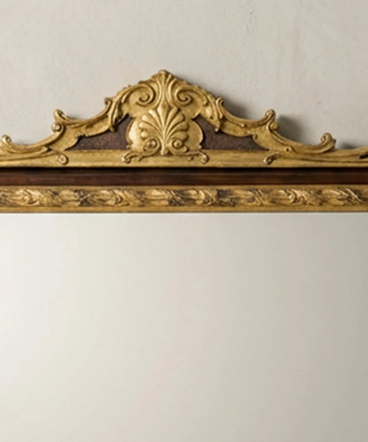 "Detalle de talla en madera dorada con forma de concha y hojas de acanto en la parte superior del espejo."