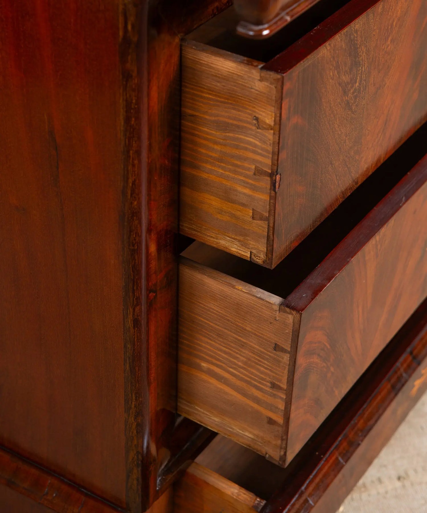 ajones de cómoda antigua abiertos mostrando ensambles manuales de cola de milano en madera maciza.