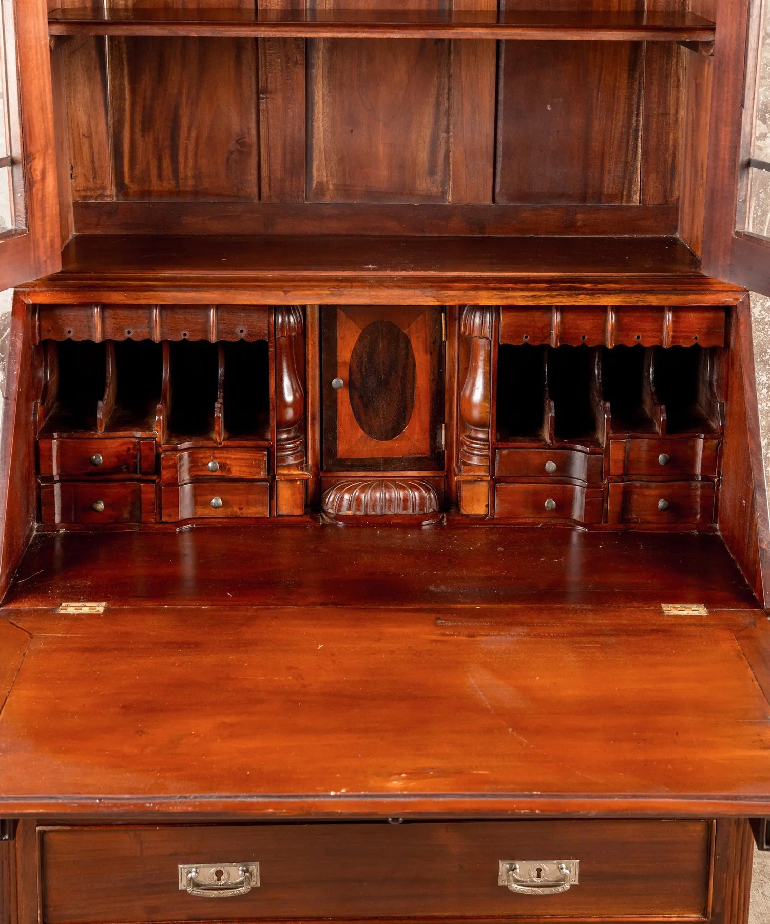 Primer plano del interior del escritorio (secretaria) mostrando cajones pequeños, nichos para cartas y puerta central con marquetería.