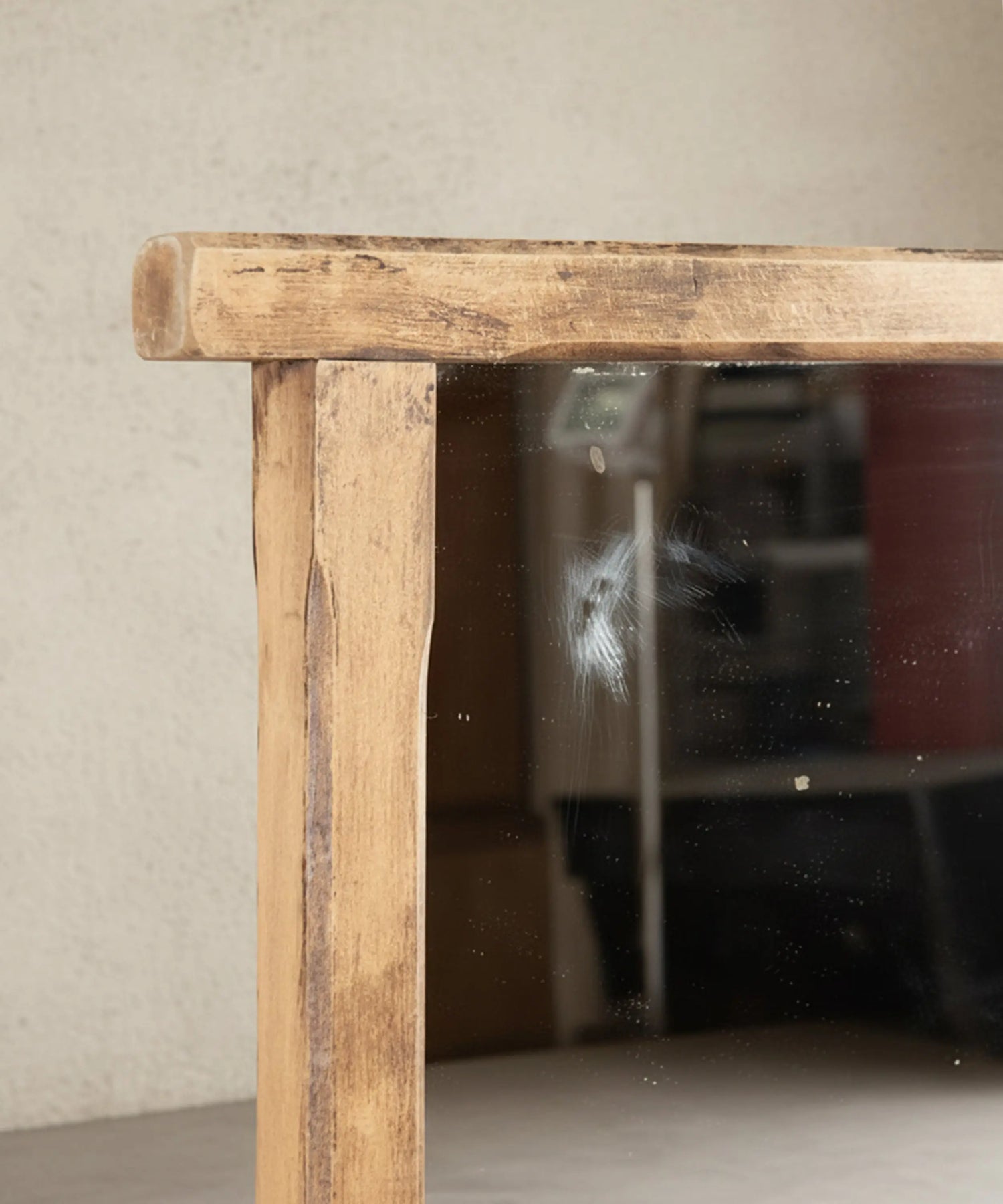 Detalle del marco de madera lavada y marca vintage en el cristal de espejo rústico.