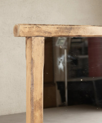 Detalle del marco de madera lavada y marca vintage en el cristal de espejo rústico.