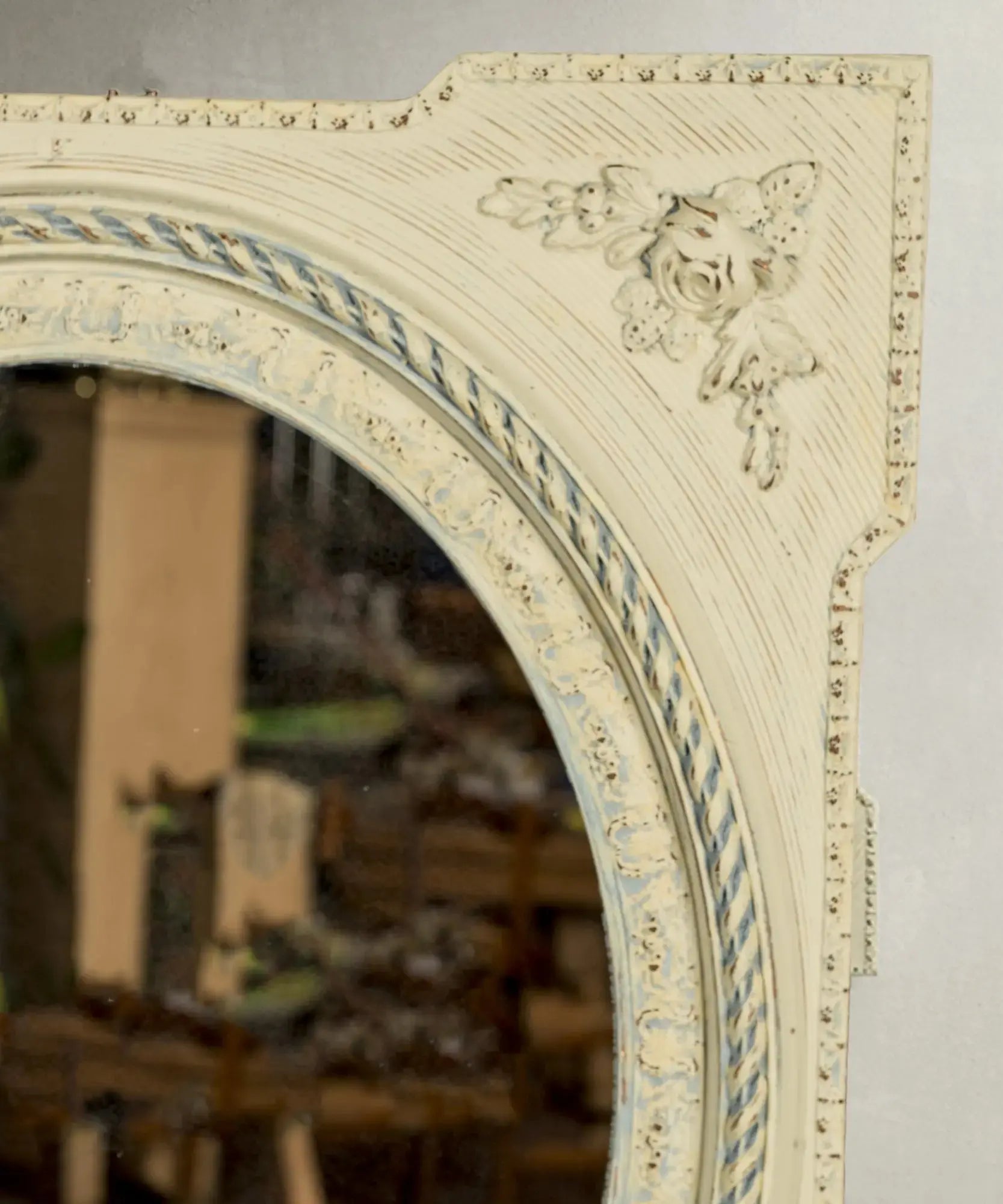 Detalle de aplique de rosas en relieve y pintura decapada en marco de espejo vintage.