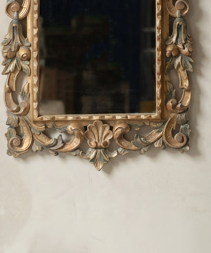 Detalle de concha y volutas talladas en la parte inferior de un espejo rococó antiguo.