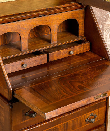 Primer plano de los nichos interiores tallados en arco y los tiradores de bronce originales de los cajones.