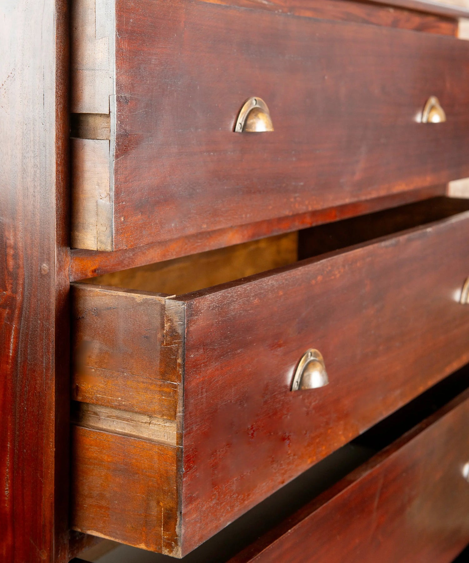 Primer plano de tiradores de concha metálicos y ensambles de cola de milano en cómoda antigua