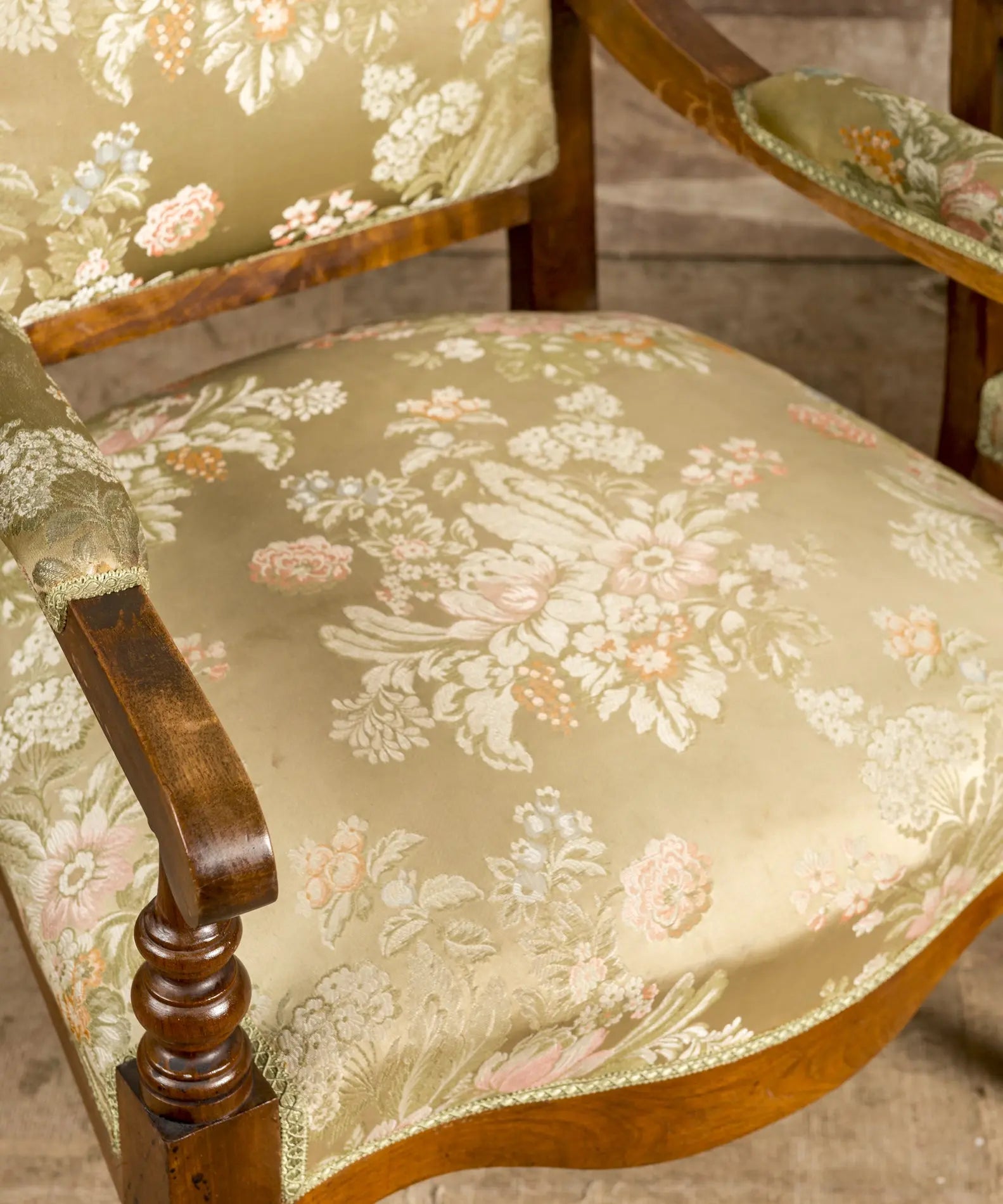 Primer plano de la talla en el copete y el tejido jacquard floral en tonos pastel de los sillones.