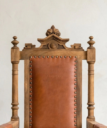 Respaldo de cuero y madera tallada con remates torneados en sillón de estilo renacentista.