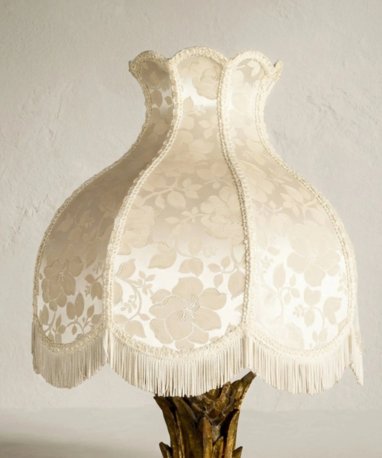 Pantalla de lámpara clásica tipo pagoda en tela adamascada beige con pasamanería y flecos largos.