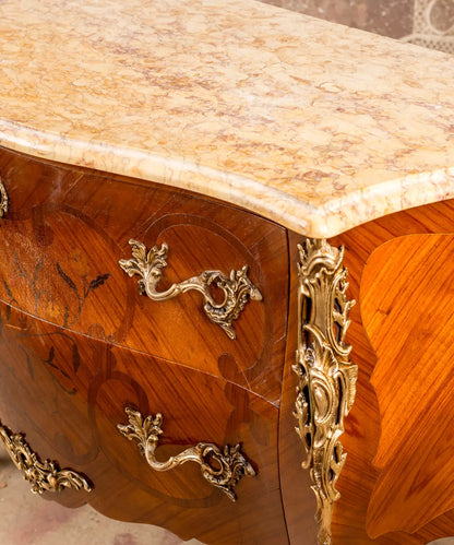 Primer plano de las aplicaciones de bronce dorado y tiradores de rocalla sobre madera de nogal.