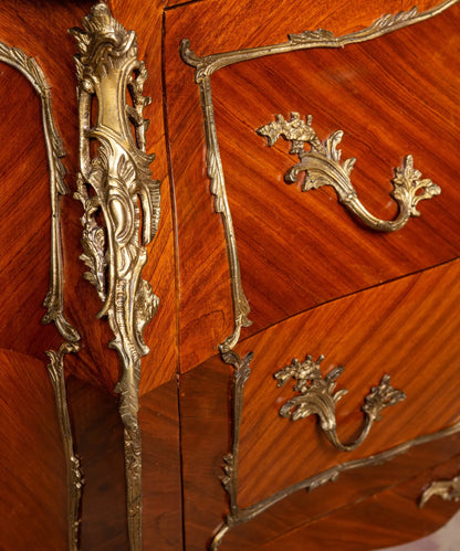 Primer plano de la marquetería en rombo y los herrajes de rocalla en bronce de una cómoda antigua francesa.