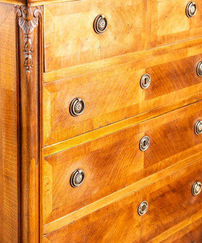 Detalle de chapa de madera dispuesta en espiga (frisage) y tiradores de anilla clásicos en mueble antiguo.