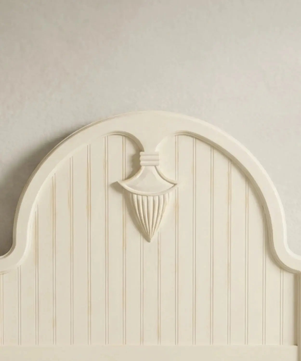 Primer plano del medallón neoclásico tallado a mano en el cabecero de la cama con acabado decapado.