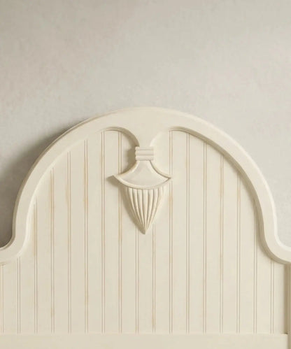 Primer plano del medallón neoclásico tallado a mano en el cabecero de la cama con acabado decapado.