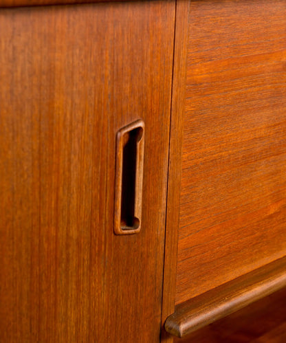 Aparador vintage de madera de teca resaltando los tiradores orgánicos y las patas cónicas.