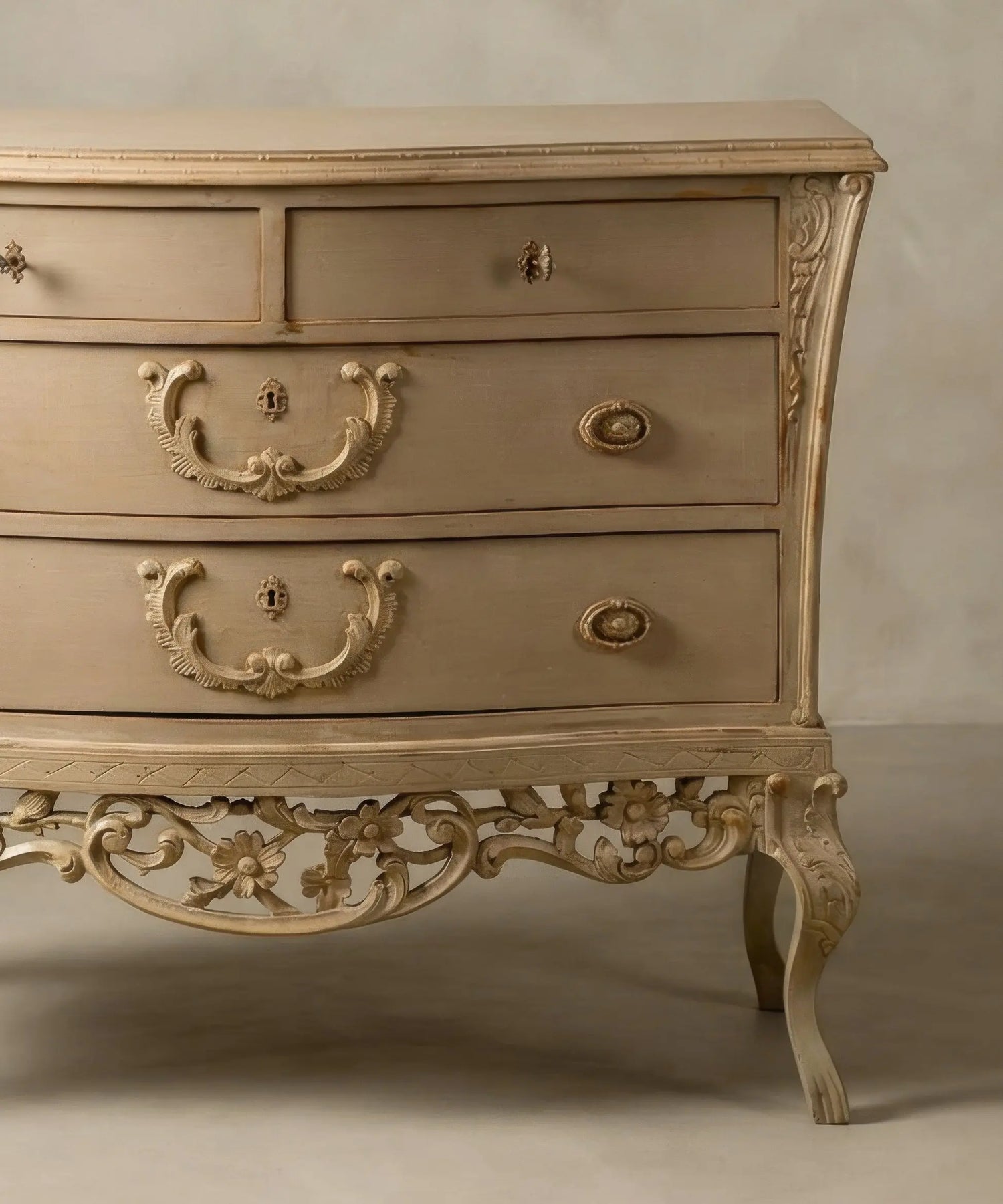 Detalle lateral de patas cabriolé y desgaste artesanal en aristas de cómoda abombada clásica.