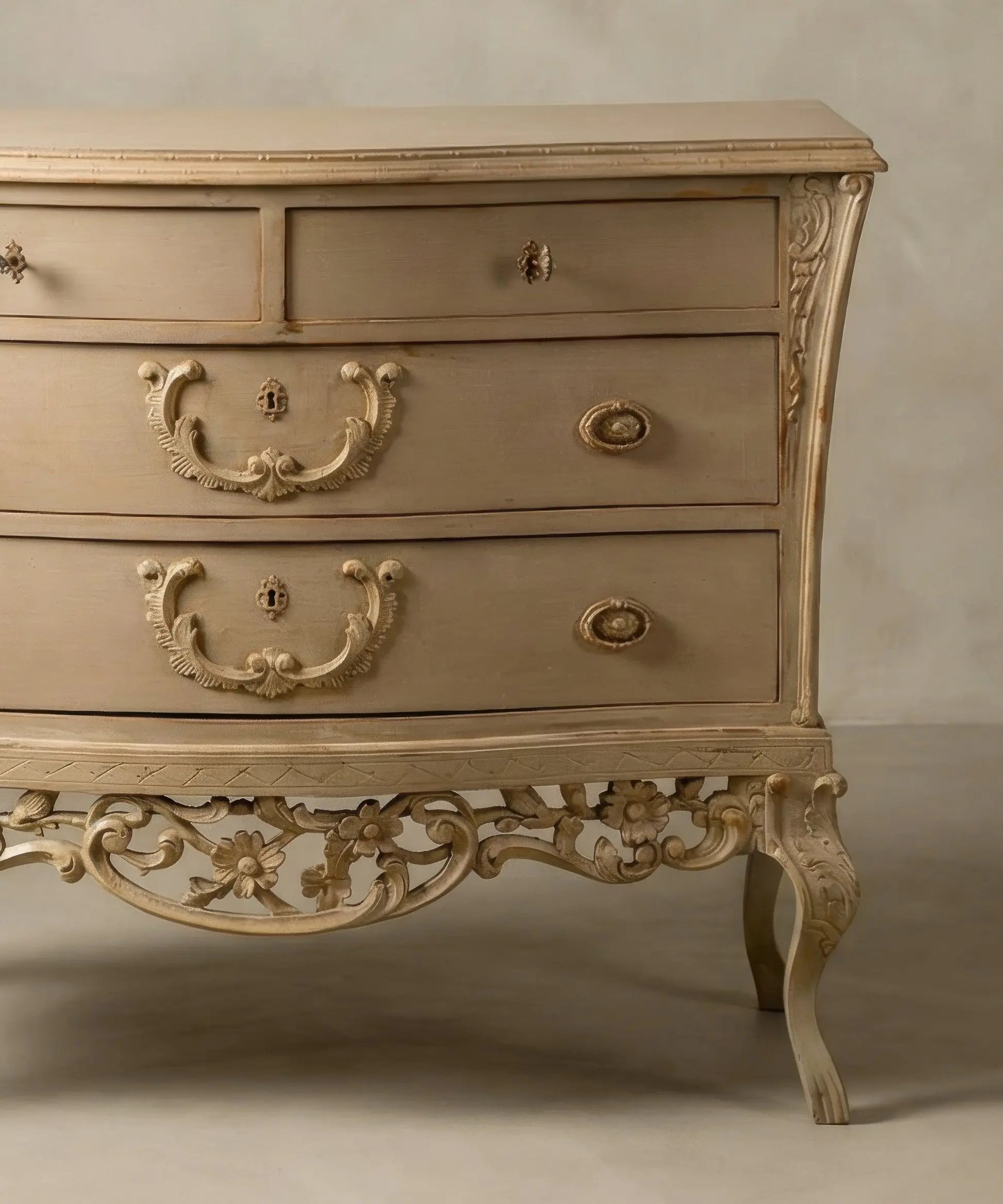 Detalle lateral de patas cabriolé y desgaste artesanal en aristas de cómoda abombada clásica.