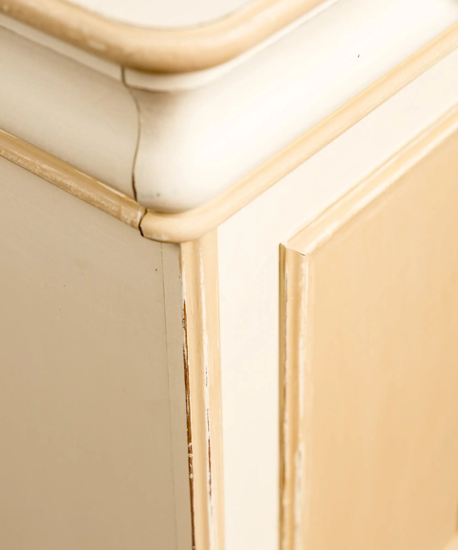 Primer plano del desgaste decapé en aristas de mueble vintage bicolor estilo shabby chic.