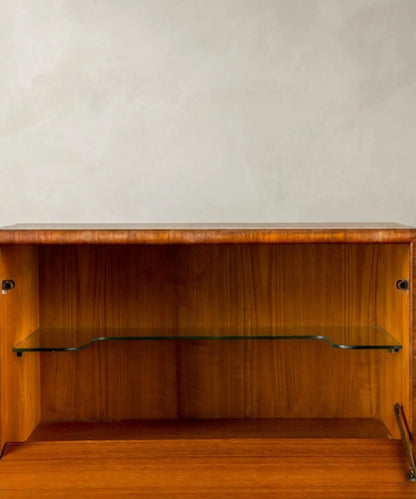 Aparador vintage de madera de teca resaltando los tiradores orgánicos y las patas cónicas.