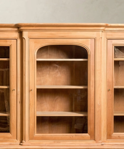 Primer plano de la puerta central arqueada y puertas laterales de cristal con estantes de madera interiores.