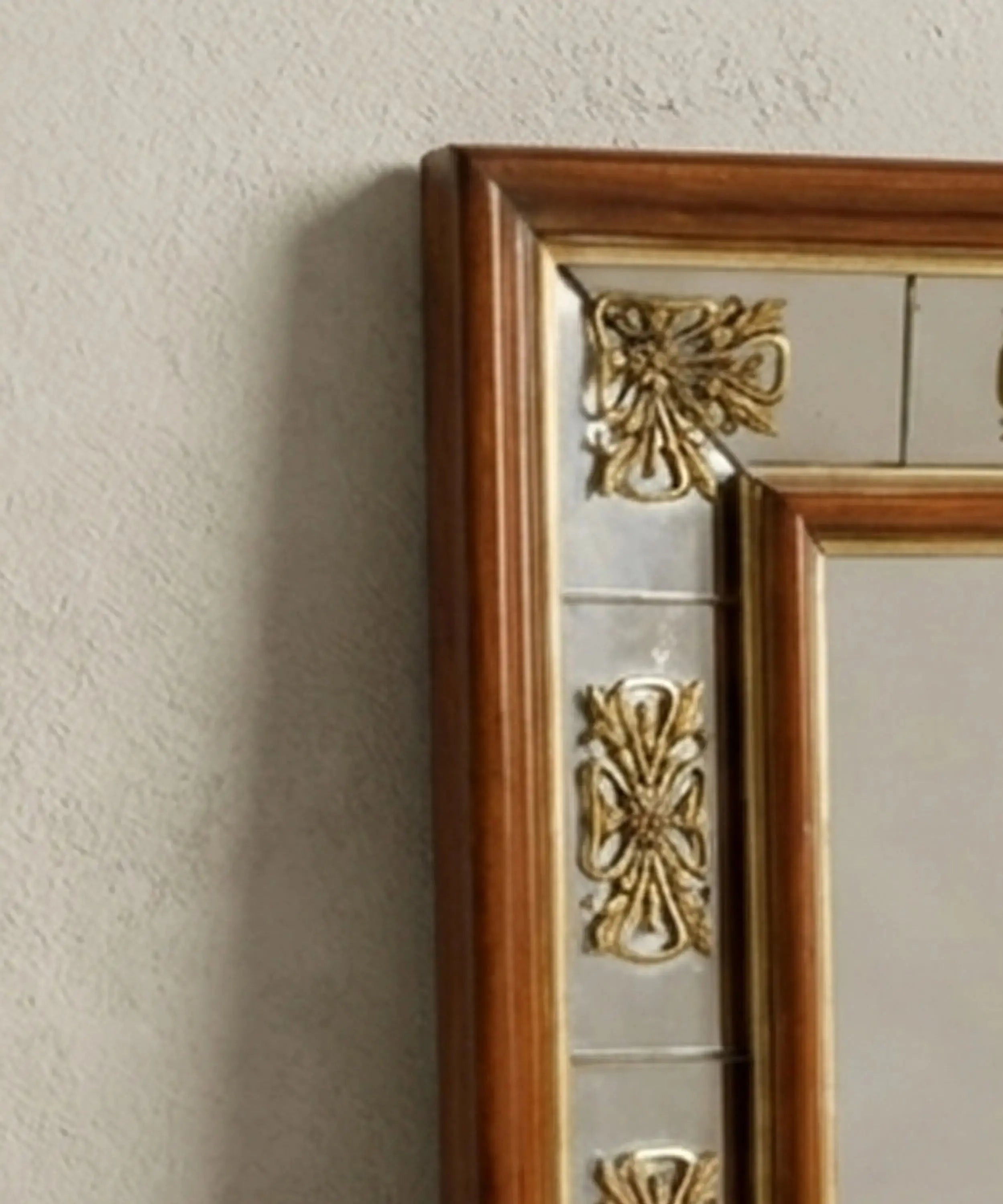 Detalle de rosetones de bronce dorado y cristal antiguo en marco de espejo neoclásico.