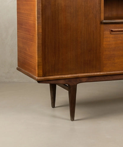 Aparador vintage de madera de teca resaltando los tiradores orgánicos y las patas cónicas.