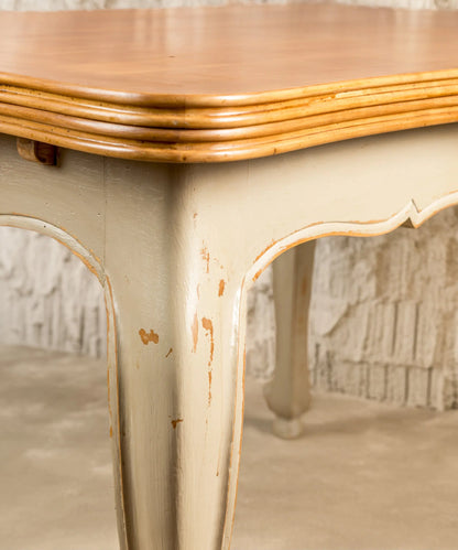 Primer plano de pata cabriolé con pintura gris y acabado decapé artesanal en mesa clásica.