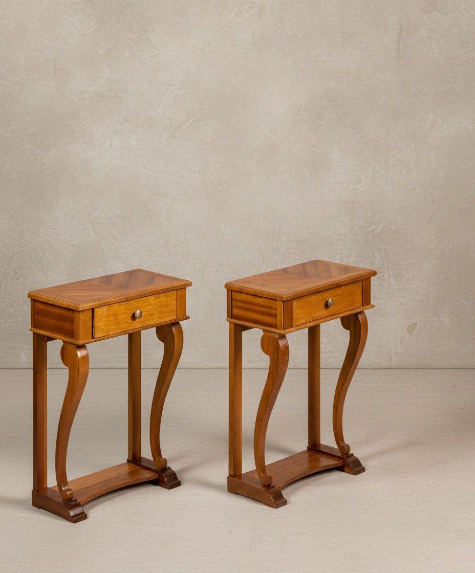 Vista lateral de las mesitas mostrando la curvatura elegante de las patas y el acabado brillante de la madera.