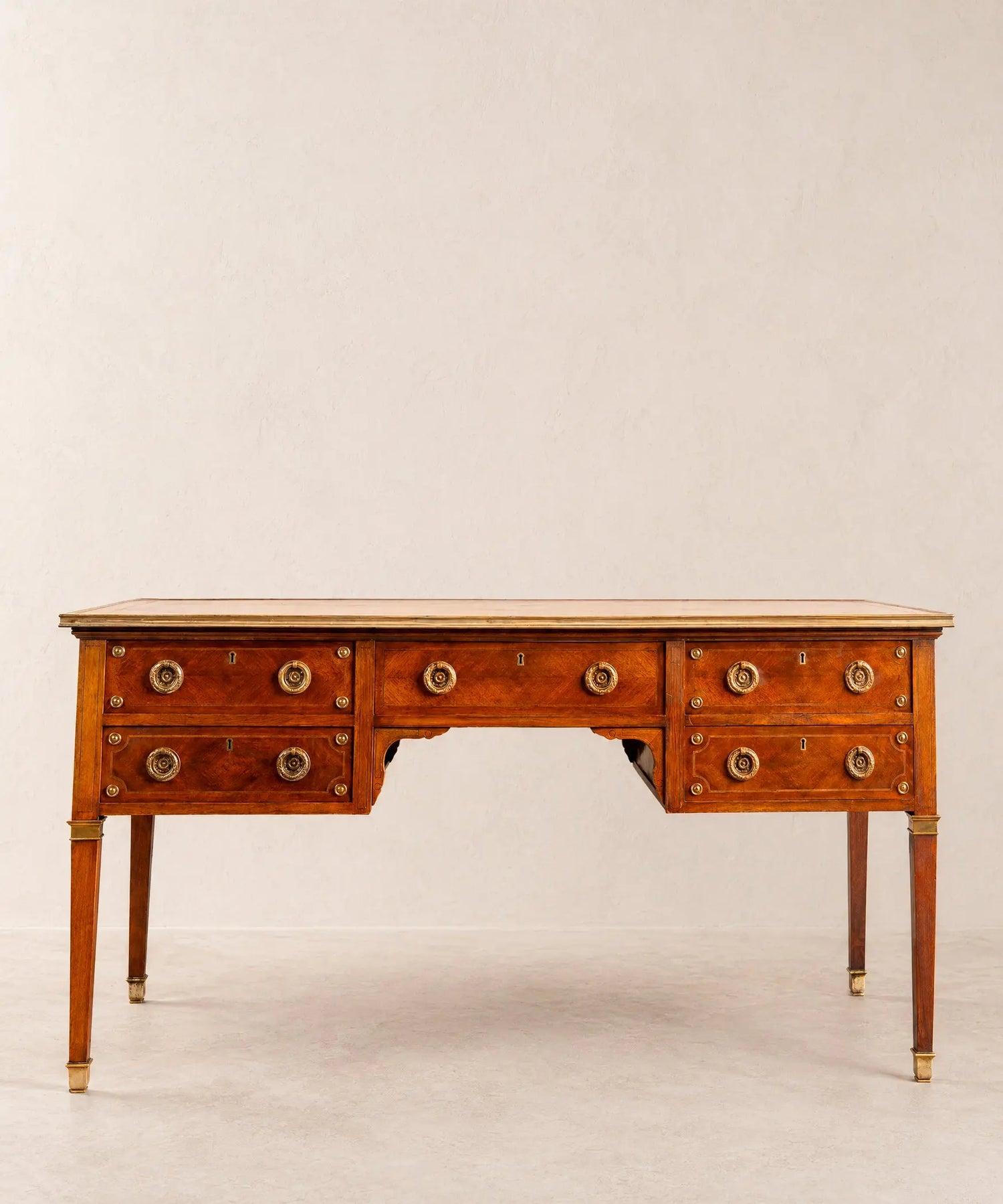 Gran escritorio de centro estilo Luis XVI de madera con cinco cajones y herrajes de bronce.