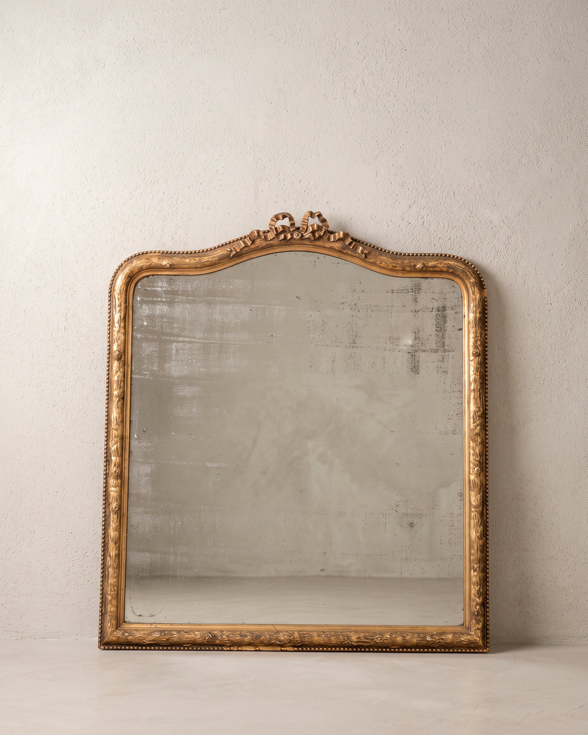 Espejo antiguo francés dorado al pan de oro con copete de lazo, vista frontal — Antique Arte y Decoración