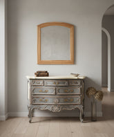 Espejo de madera natural sobre cómoda vintage gris en un salón elegante
