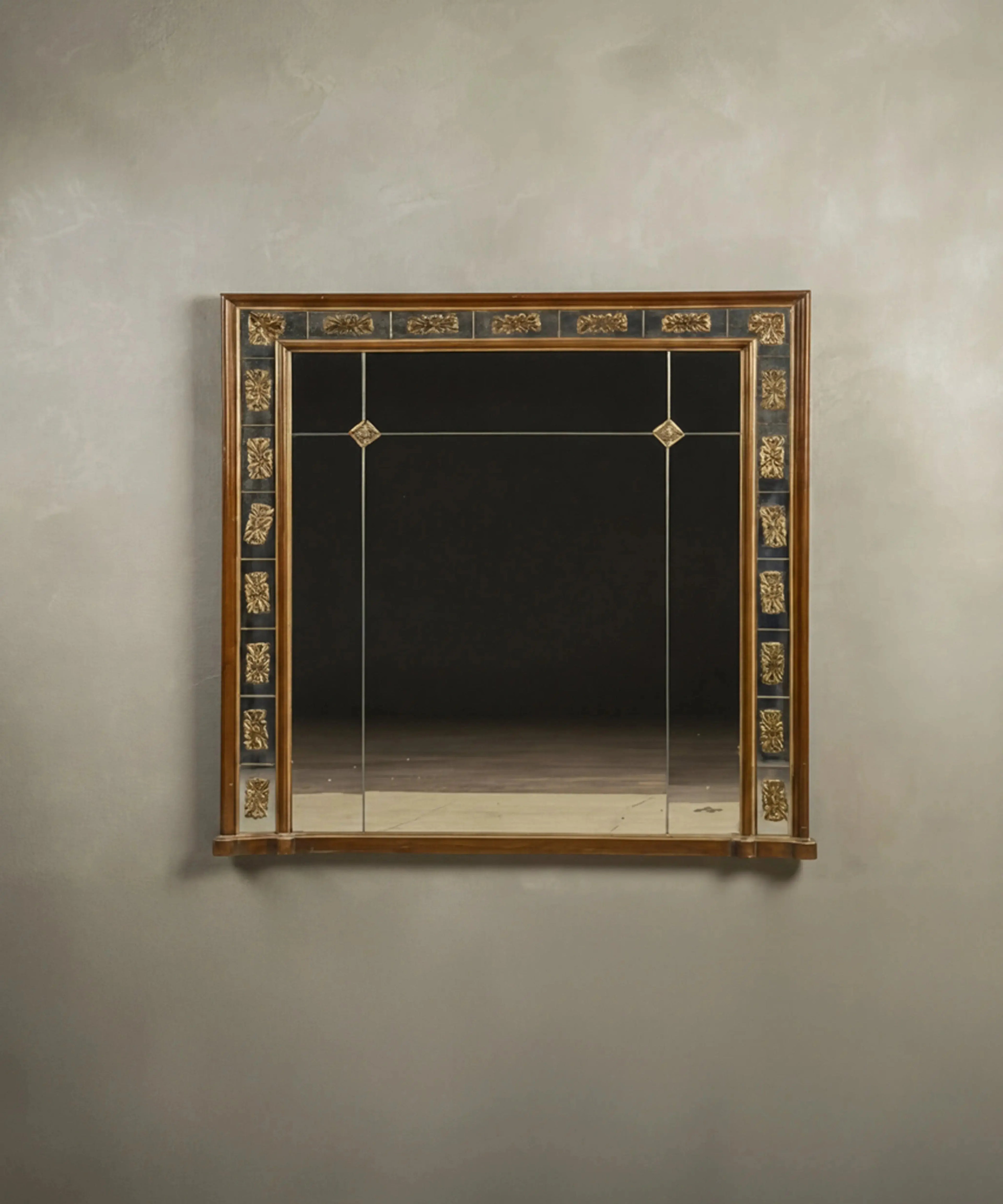 Espejo de pared vintage estilo Imperio con marco de cristal segmentado y apliques dorados.