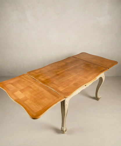 Mesa de comedor extensible antigua totalmente abierta mostrando alas laterales y tablero de madera.