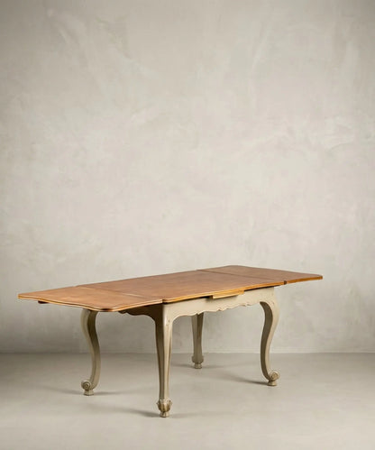 Mesa de comedor extensible antigua totalmente abierta mostrando alas laterales y tablero de madera.