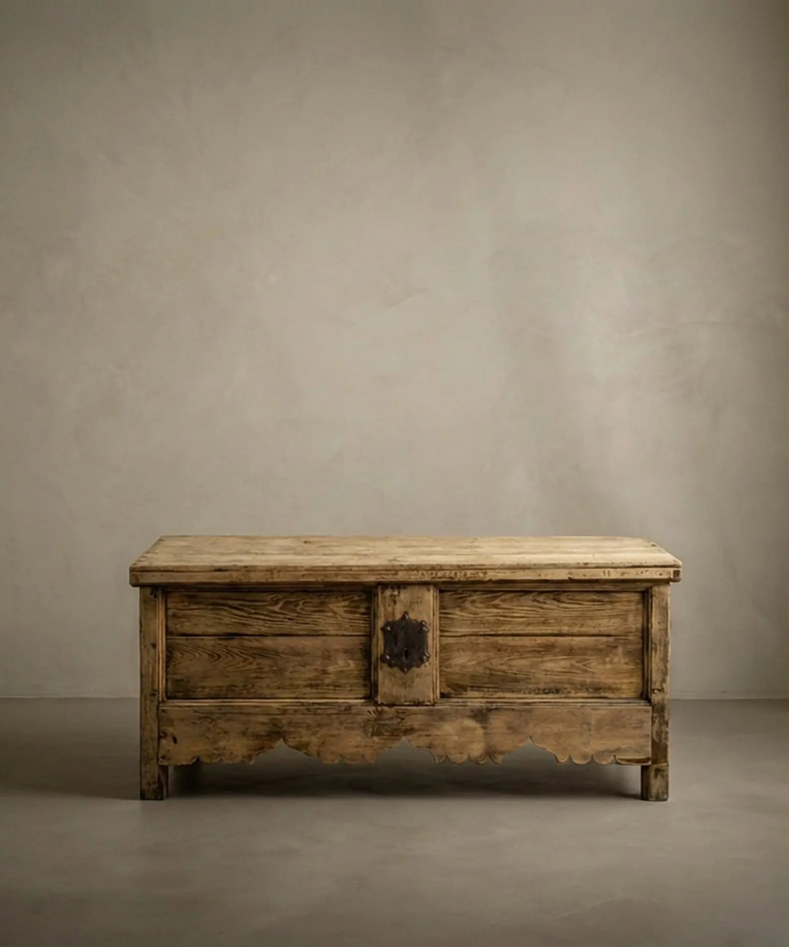 Arcón rústico de madera maciza siglo XIX con faldón festoneado y cerradura de forja en ambiente minimalista.