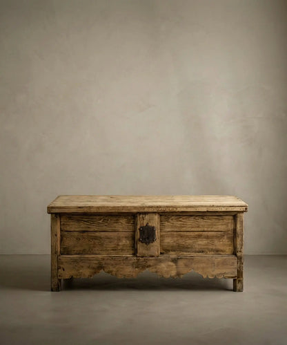 Arcón rústico de madera maciza siglo XIX con faldón festoneado y cerradura de forja en ambiente minimalista.