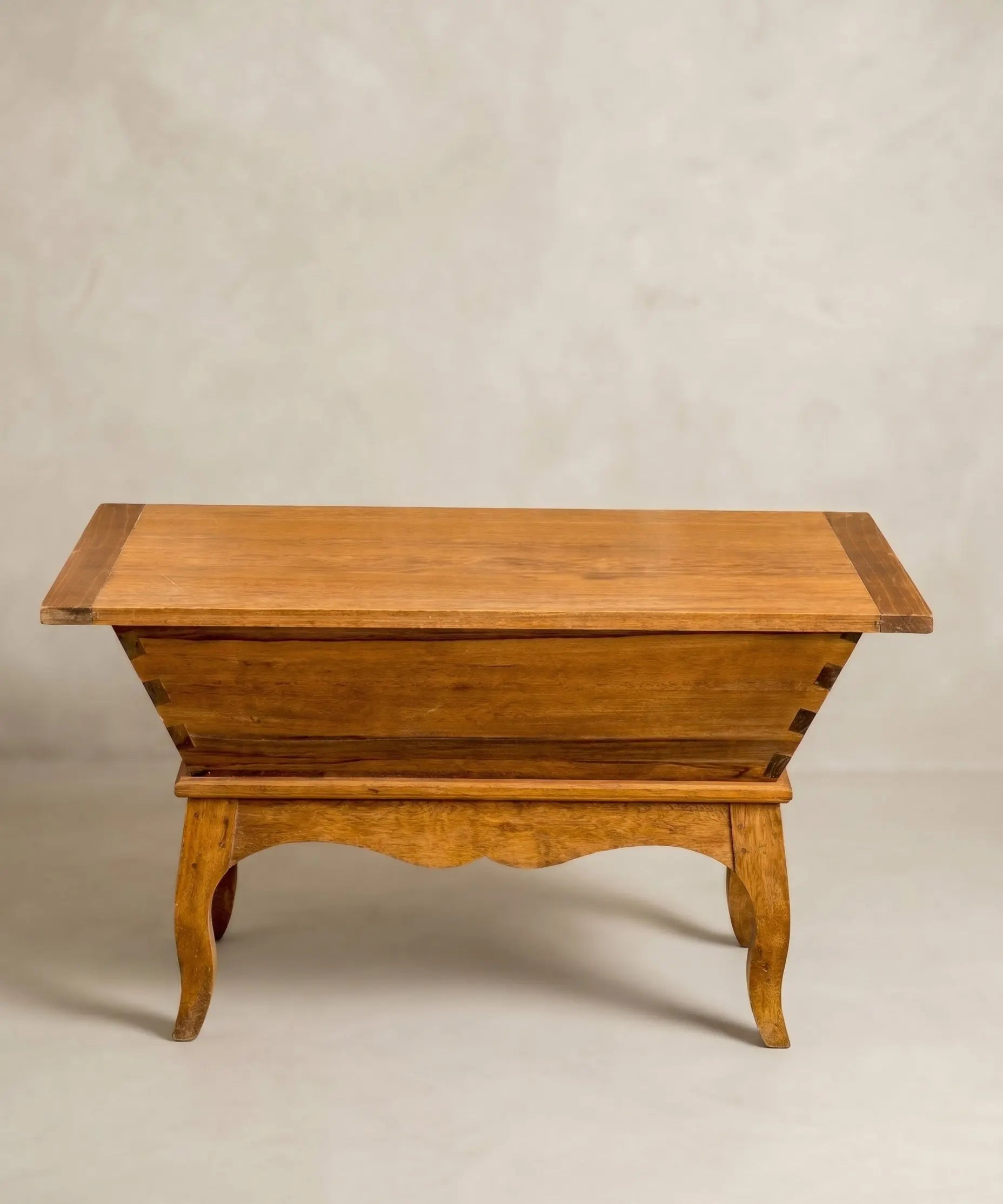 Mesa antigua tipo artesa de madera maciza con patas curvas y tapa plana estilo rústico.