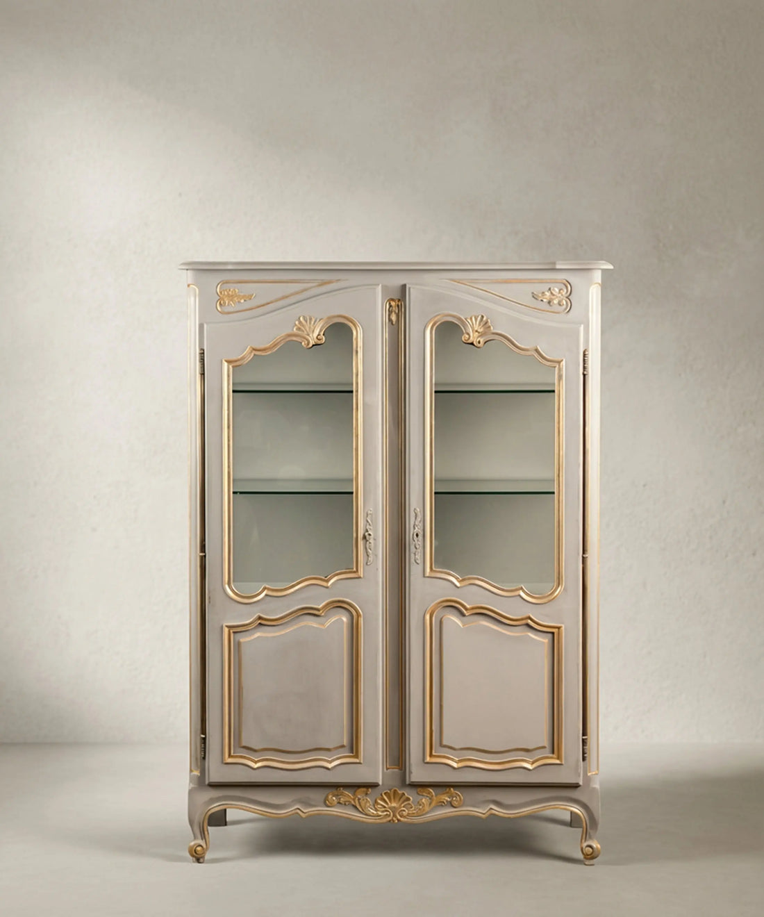 Vitrina vintage de madera estilo Luis XV pintada de gris con molduras doradas.