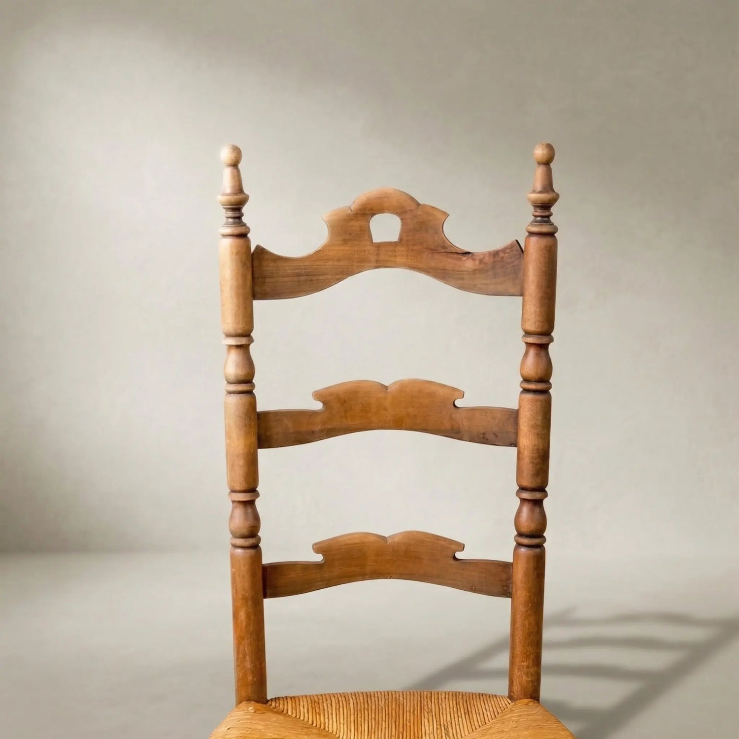 Primer plano del respaldo de madera ondulada y pináculos torneados en silla rústica.