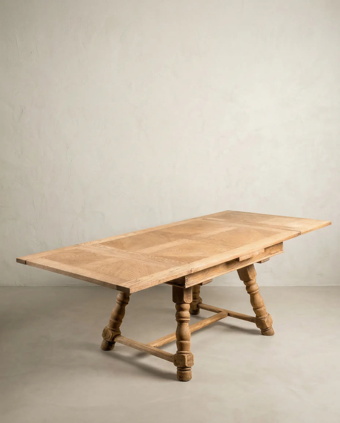 Mesa de comedor extensible de madera de roble natural con alas desplegadas y marquetería superior.