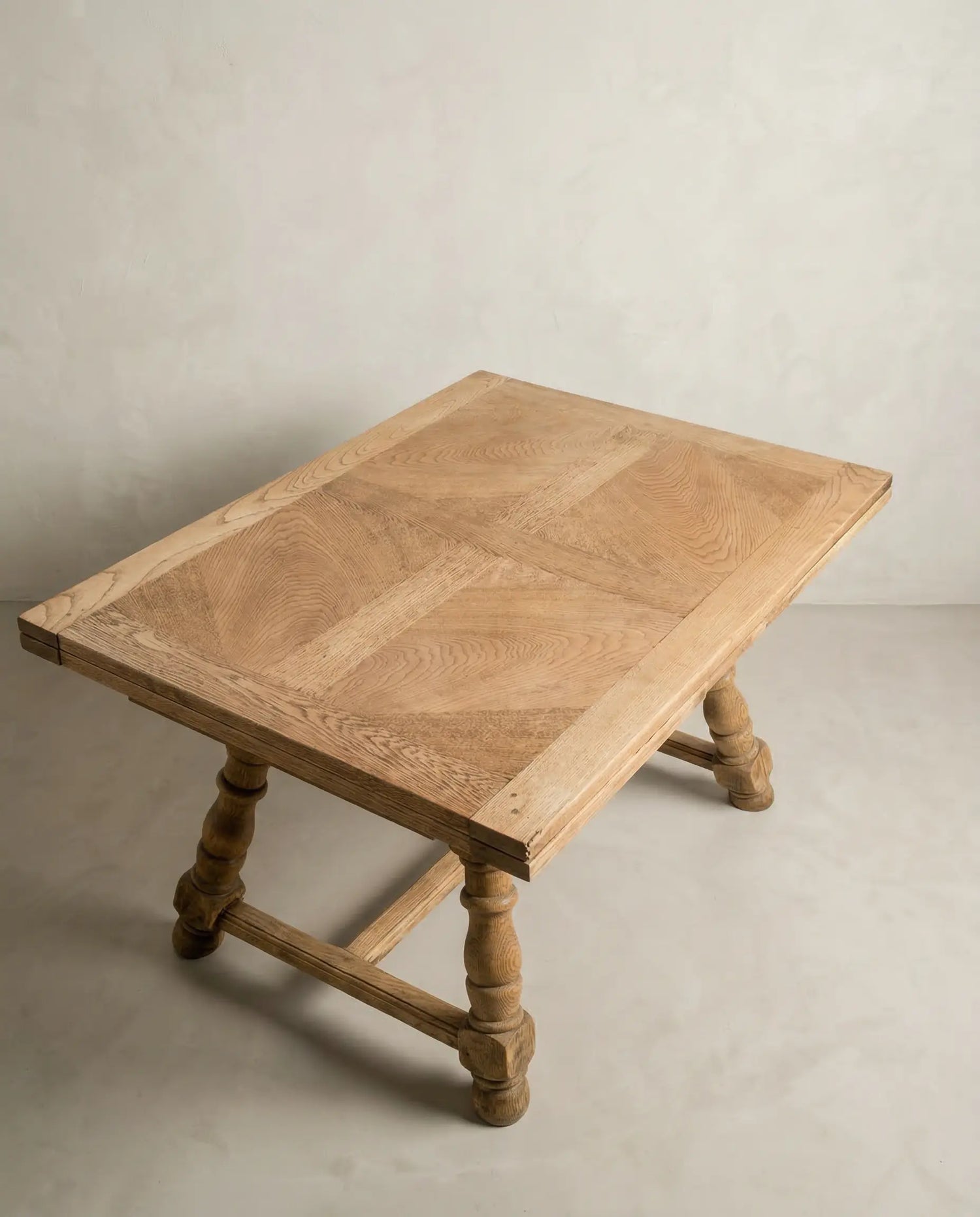 Mesa de comedor rústica cerrada mostrando las potentes patas torneadas y el acabado en madera clara.