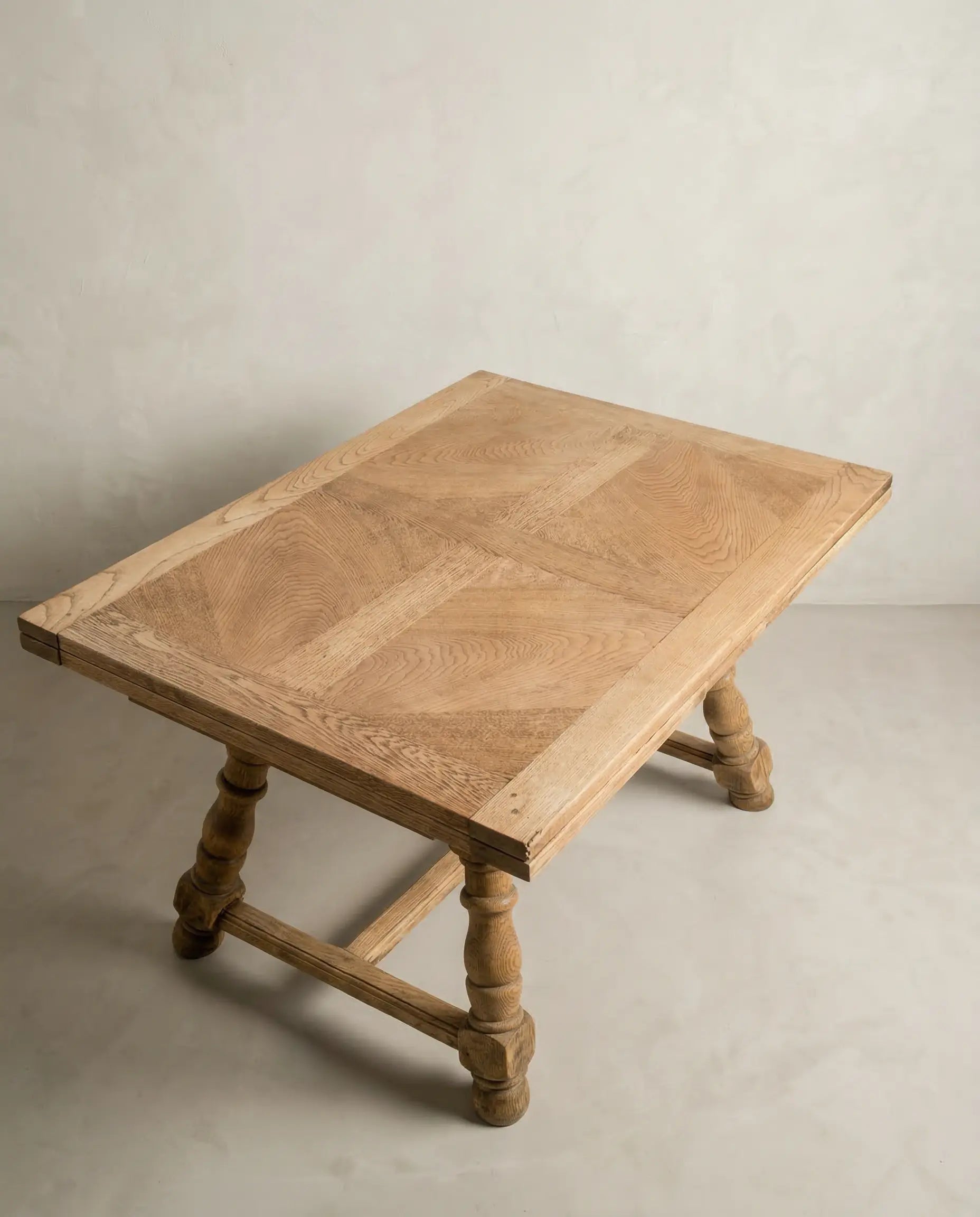 Mesa de comedor rústica cerrada mostrando las potentes patas torneadas y el acabado en madera clara.